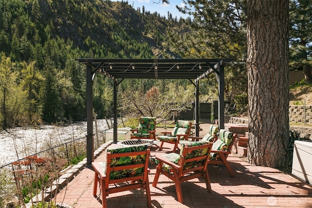 view of patio featuring a pergola, a forest view, and fence
