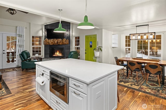 kitchen with a kitchen island, white cabinetry, a fireplace, and wood finished floors