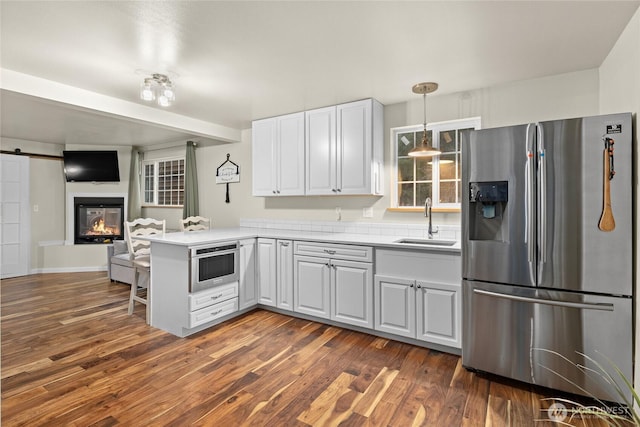 kitchen featuring a barn door, dark wood finished floors, stainless steel fridge with ice dispenser, a peninsula, and a sink