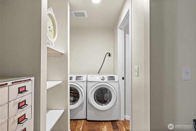 laundry room featuring laundry area, visible vents, wood finished floors, and washing machine and clothes dryer