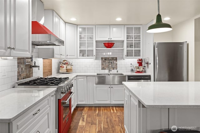 kitchen featuring a sink, white cabinets, appliances with stainless steel finishes, wall chimney range hood, and light wood-type flooring