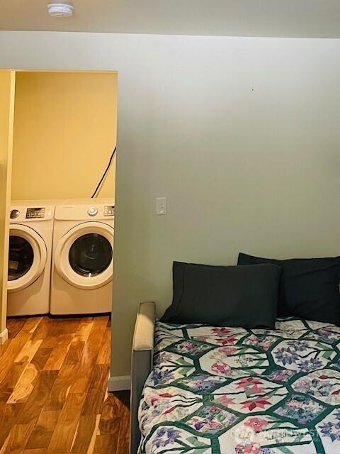 clothes washing area with wood finished floors, laundry area, and separate washer and dryer