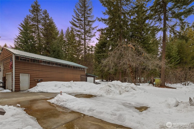 yard covered in snow featuring an outbuilding and a garage