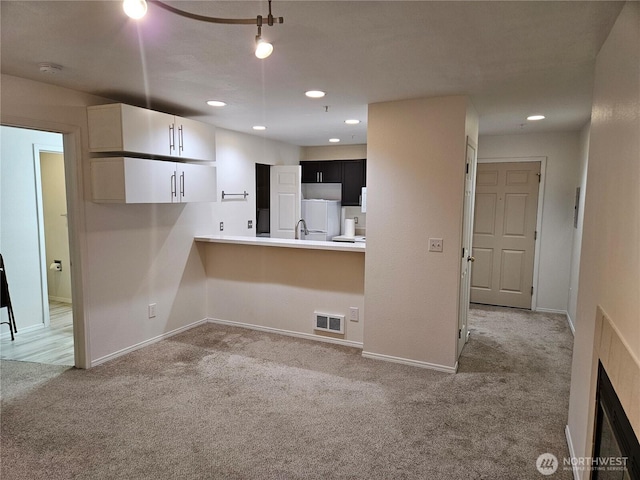 kitchen with baseboards, visible vents, and light colored carpet