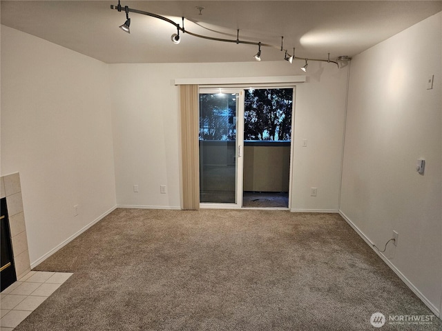 interior space featuring a tiled fireplace, rail lighting, and baseboards