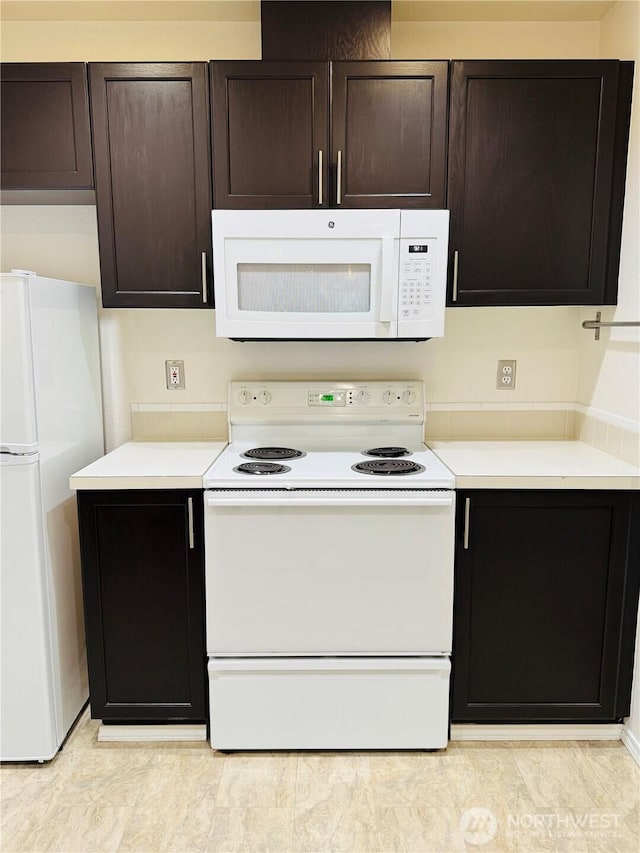 kitchen with white appliances, light countertops, and dark brown cabinets