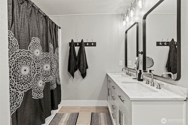 bathroom featuring double vanity, baseboards, a sink, and wood finished floors