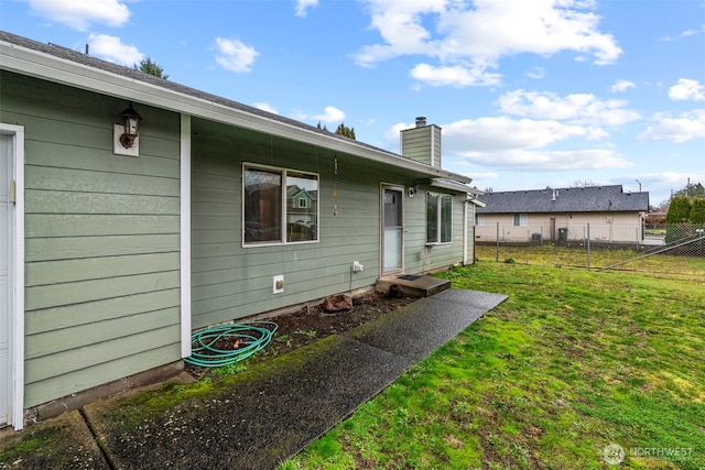 back of property featuring a yard, fence, and a chimney