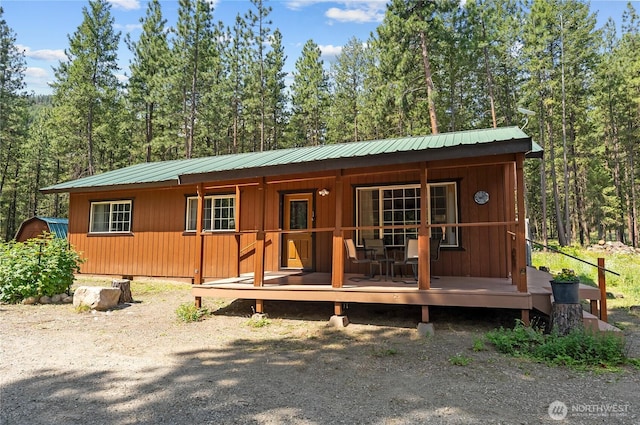 view of front of home with metal roof, a porch, and a wooded view