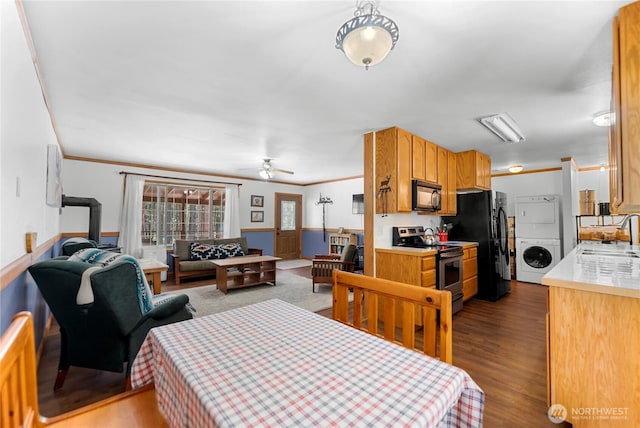 dining room featuring stacked washer and clothes dryer, crown molding, and wood finished floors