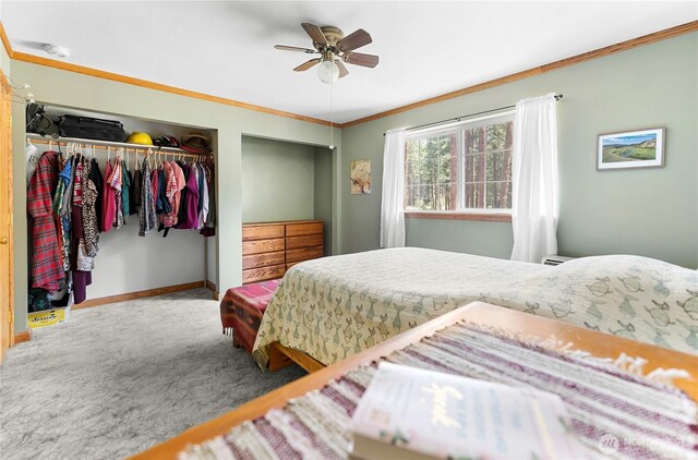 carpeted bedroom featuring a closet, baseboards, a ceiling fan, and crown molding