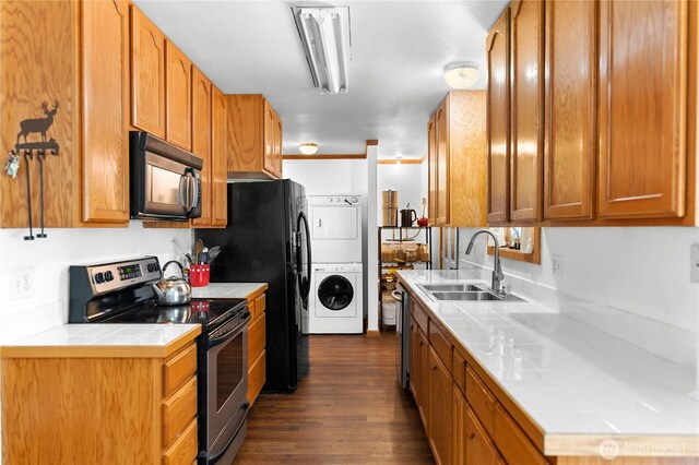 kitchen featuring stainless steel electric stove, dark wood-style flooring, a sink, stacked washer and dryer, and black microwave