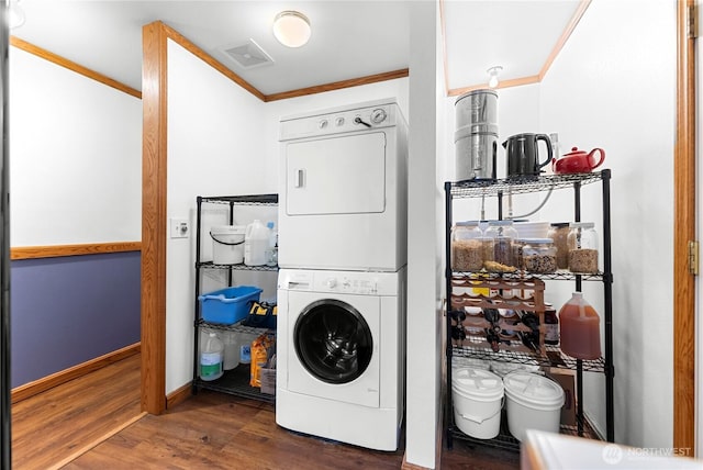 clothes washing area featuring visible vents, stacked washer and clothes dryer, ornamental molding, wood finished floors, and laundry area