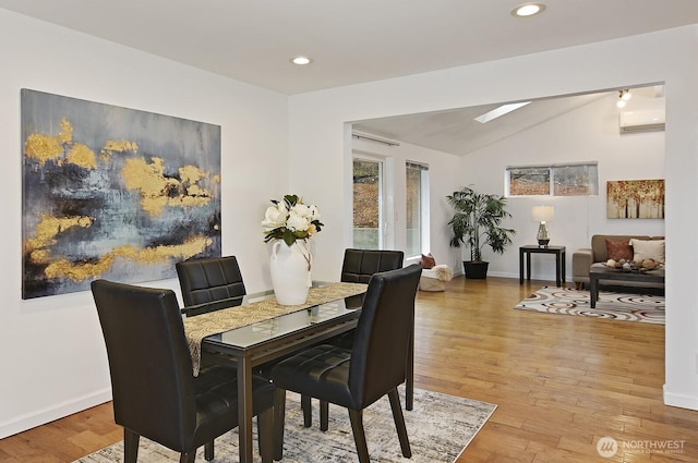 dining room featuring vaulted ceiling with skylight, recessed lighting, light wood-type flooring, and baseboards