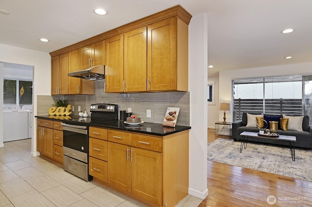 kitchen featuring decorative backsplash, washer and dryer, stainless steel range with electric stovetop, and under cabinet range hood