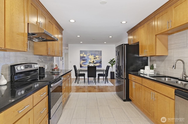 kitchen featuring recessed lighting, under cabinet range hood, stainless steel appliances, a sink, and backsplash