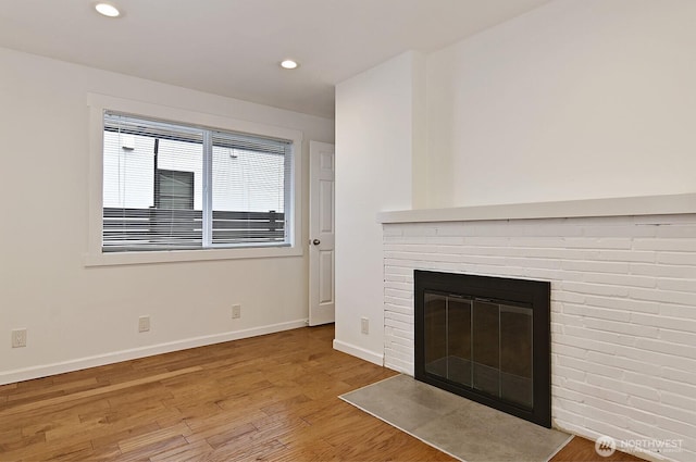 unfurnished living room featuring a fireplace, baseboards, wood finished floors, and recessed lighting