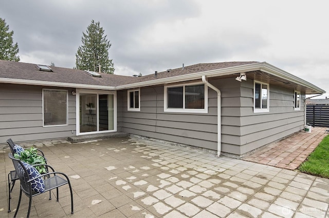 rear view of house featuring roof with shingles and a patio area