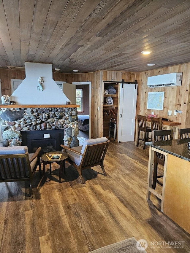 living room with wood finished floors, a barn door, wooden ceiling, and a wall unit AC