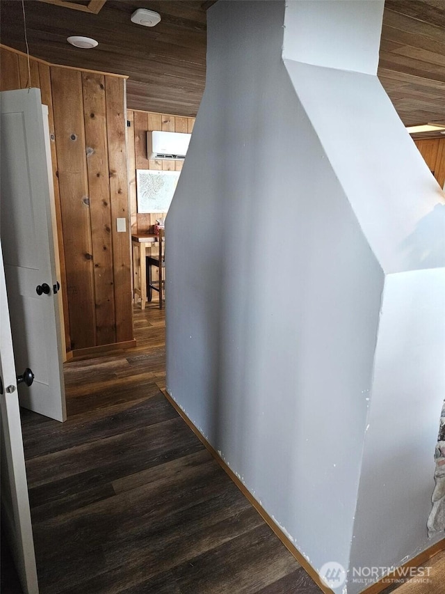 corridor with an AC wall unit, wood finished floors, wood ceiling, and wooden walls