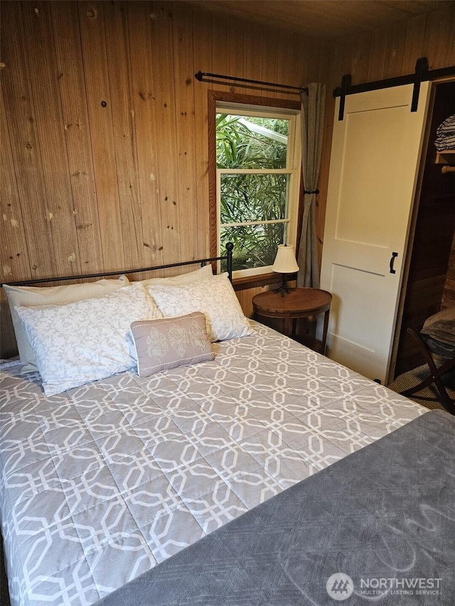 bedroom with wood walls and a barn door