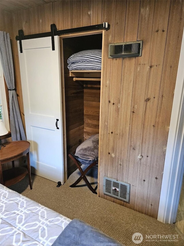 interior space featuring carpet floors, wooden walls, visible vents, and a closet