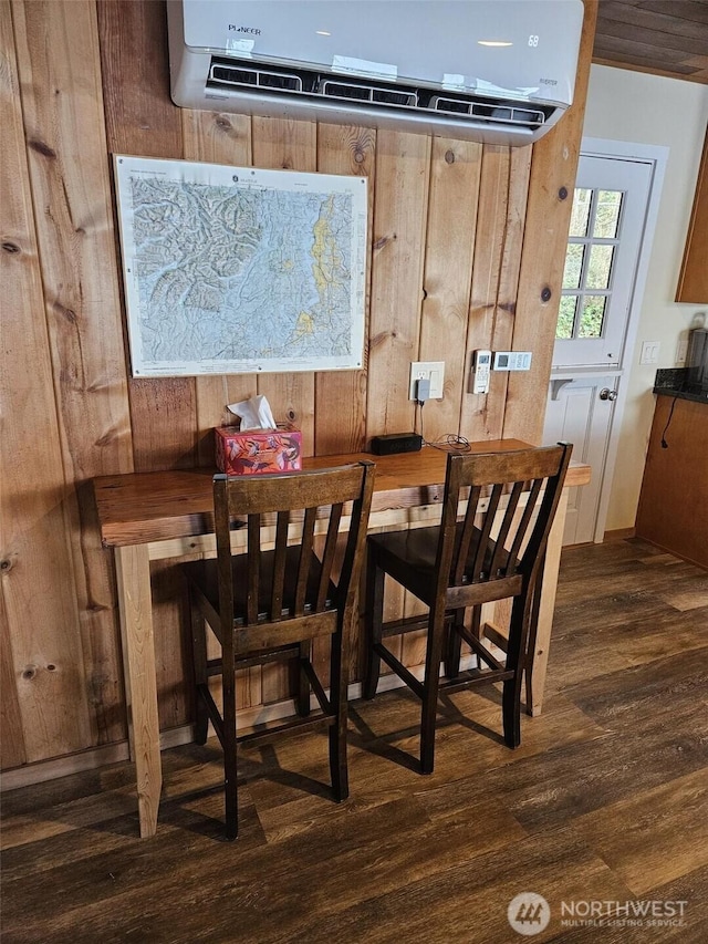 dining area with dark wood-style flooring and a wall unit AC