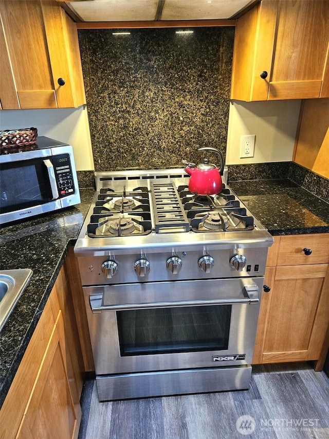 kitchen with appliances with stainless steel finishes, dark wood-style flooring, and brown cabinets