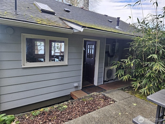 property entrance with ac unit, a shingled roof, and a chimney