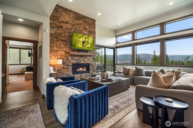 living room with recessed lighting, a fireplace, a high ceiling, and wood finished floors