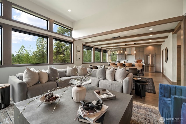 living room featuring a wealth of natural light, recessed lighting, beam ceiling, and wood finished floors