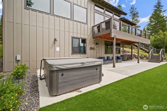 rear view of house with a patio, stairs, a yard, board and batten siding, and a hot tub