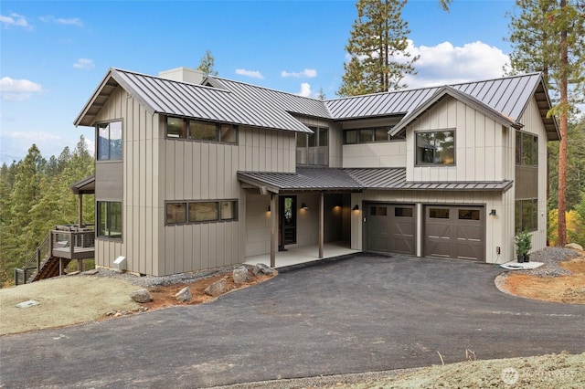 modern inspired farmhouse with metal roof, a standing seam roof, and driveway