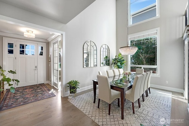 dining room with wood-type flooring, an inviting chandelier, and baseboards