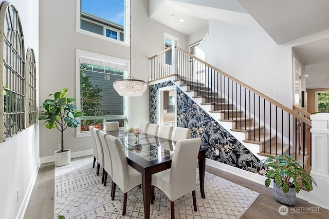 dining area with stairs, a high ceiling, hardwood / wood-style flooring, and baseboards