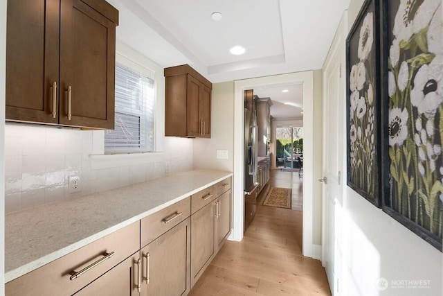 interior space featuring light stone counters, recessed lighting, backsplash, light wood-style flooring, and high end refrigerator