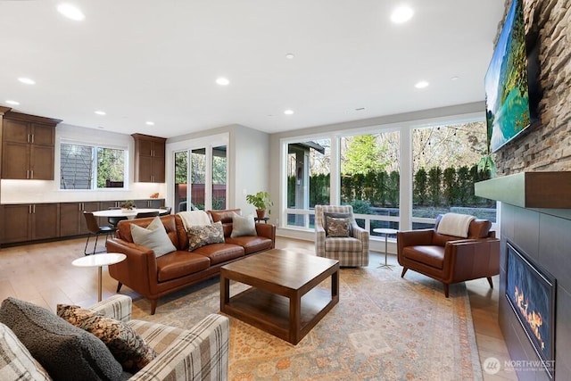 living area with recessed lighting, a fireplace, and light wood finished floors