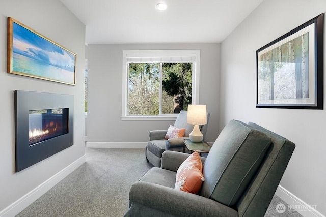 sitting room with carpet, baseboards, and a glass covered fireplace