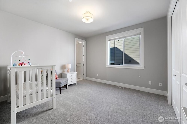 bedroom featuring a nursery area, carpet, visible vents, and baseboards