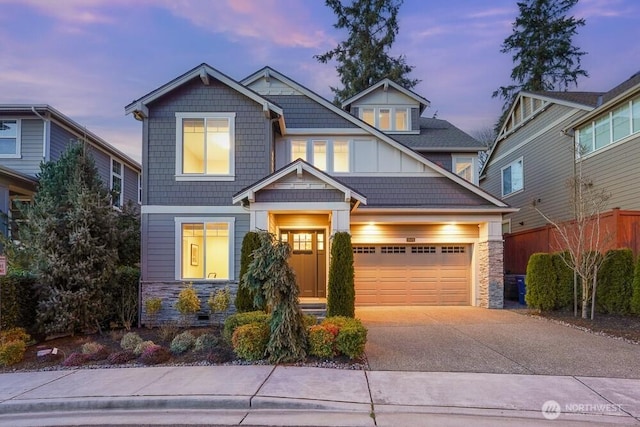 craftsman-style home with board and batten siding, stone siding, an attached garage, and concrete driveway