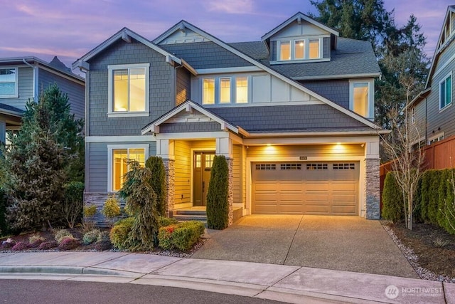 craftsman-style home featuring a garage, stone siding, driveway, and board and batten siding