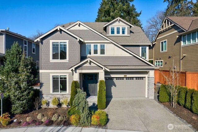 craftsman inspired home with an attached garage, a shingled roof, fence, driveway, and stone siding