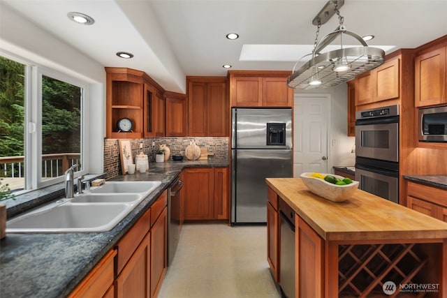 kitchen with a sink, butcher block countertops, appliances with stainless steel finishes, a skylight, and open shelves