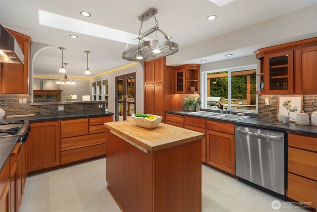 kitchen with stainless steel dishwasher, wall chimney range hood, light floors, and wood counters