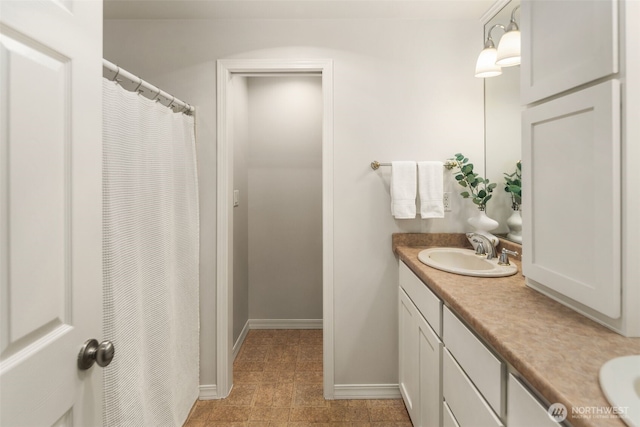 bathroom with double vanity, baseboards, and a sink