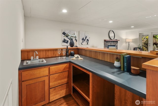 bar featuring a sink, dark wood finished floors, recessed lighting, a stone fireplace, and indoor wet bar