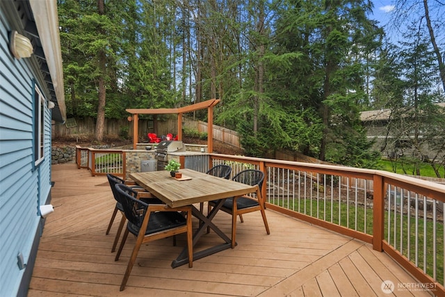 wooden terrace with grilling area, outdoor dining space, and a fenced backyard