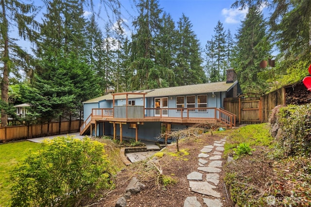 rear view of property with a deck, stairway, a fenced backyard, and a chimney