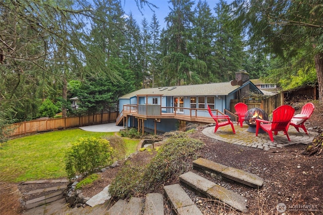 rear view of house featuring a patio, an outdoor fire pit, a fenced backyard, a deck, and a lawn