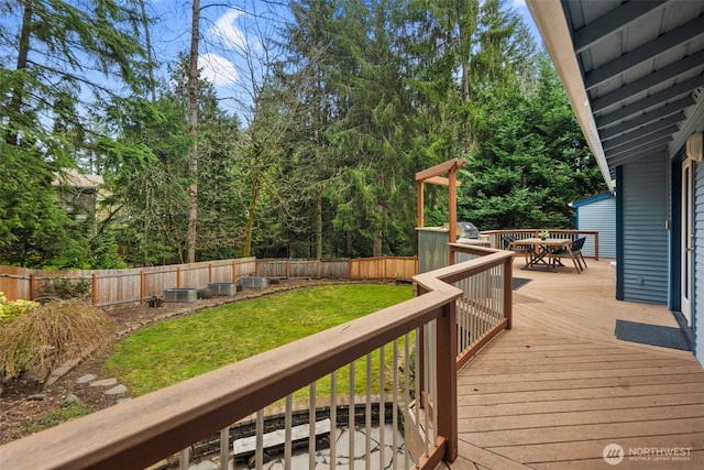 wooden terrace with outdoor dining area, a lawn, central AC unit, and a fenced backyard